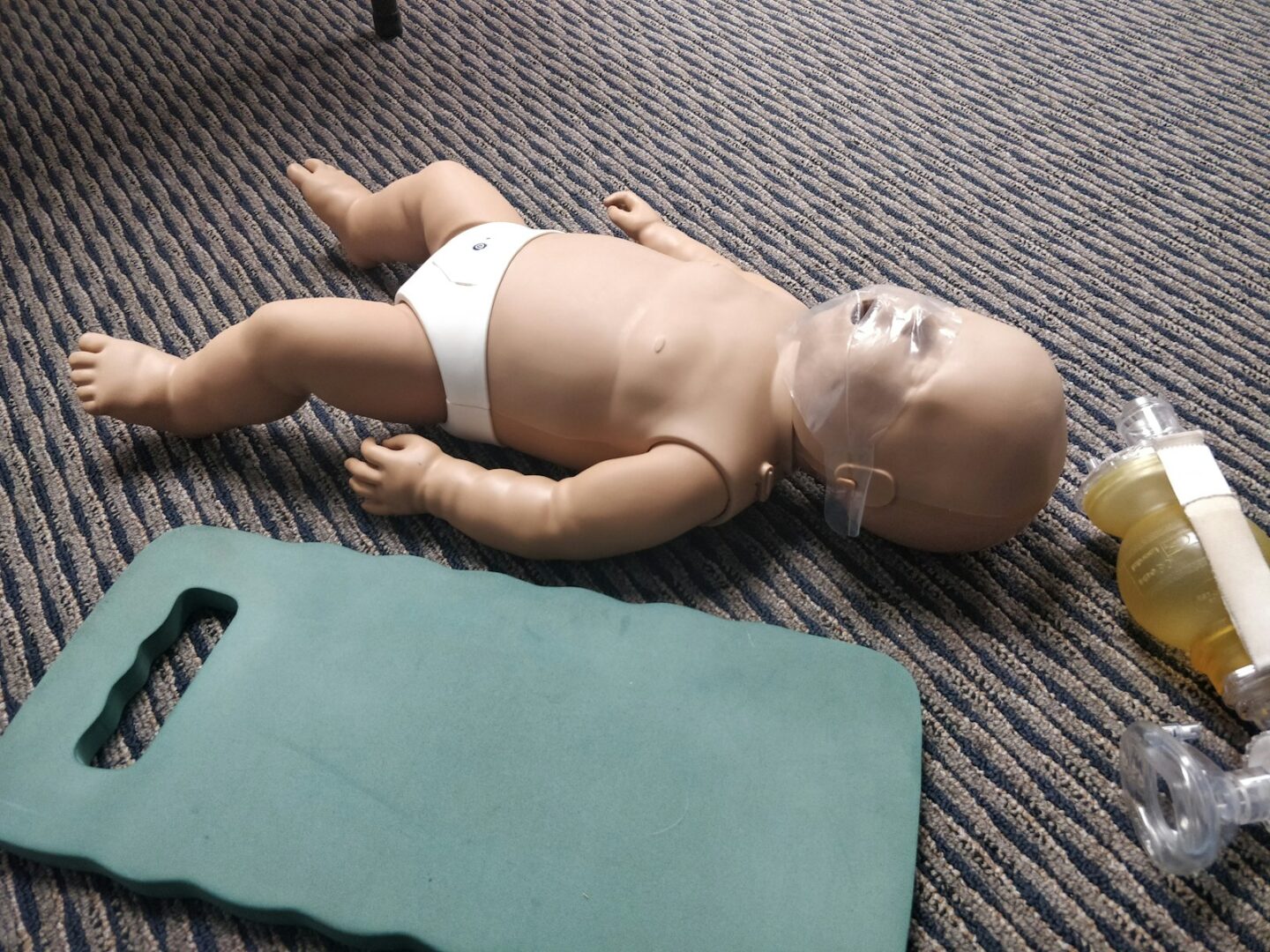 a baby doll laying on the floor next to a bottle